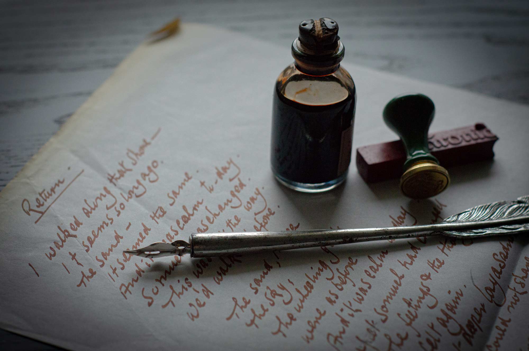 classic feather pen and ink with a rubber stamp on a hand-written note
